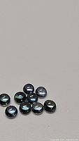 Photo showing 11 loose natural round cabochon blue sapphire gemstones on a neutral grey surface.