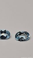 Close-up photo of the pair of oval cut sky blue topaz gemstones showing their clarity and color.