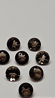 Eight round calibrated Smokey Quartz gemstones arranged closely, showing their faceted surface and dark smoky color.