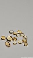 Photo showing a collection of smooth, polished natural golden citrine cabochon gemstones in various small sizes and shapes.