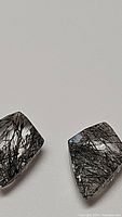 Close-up front view of two kite cut black rutilated quartz stones with dense black needle inclusions