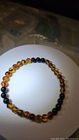 Top down view of stretchy bracelet showing alternating beads of natural Baltic piebald amber and natural jet black onyx, strung on elastic cord.