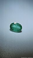 Close-up photo of a natural oval cut emerald gemstone showing its rich green color and polished facets.