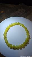 Close-up top view of natural lemon jade bead bracelet, arranged in circle on white background