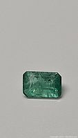 Close-up front view of the rectangular natural African emerald showing color and inclusions.