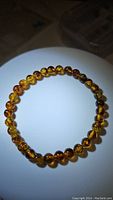 Top view of the natural Baltic amber stretchy bracelet showing round polished beads with piebald amber colors and inclusions under bright lighting.