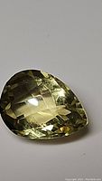 Close-up image of a natural lemon citrine gemstone showing the pear shape and checkerboard cut facets enhancing brilliance.