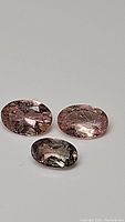 Three oval cut natural pastel peach tourmaline gemstones with slight variation in color and visible inclusions