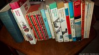 A photo showing 18 used books on a wooden table, mostly about aviation and military history with colorful book spines.