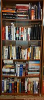 Full view of bookshelf filled with arranged books on five shelves showing diverse titles and genres, mainly history and biography.