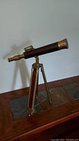 Photo of a decorative brass and wood telescope mounted on a tripod.
