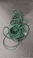 Top view of coiled long green extension cord on textured black surface