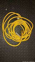 Photo of yellow extension cord coiled on a black textured surface.