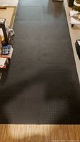 Photo showing multiple black foam floor squares connected on a floor, forming a large padded area.