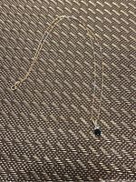 Photo showing the full length of the 10kt gold chain with a black sapphire pendant on a textured surface.