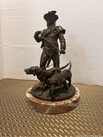Full view of bronze huntsman and two dogs on marble base, front angle