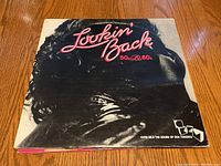 Front cover of 'Lookin Back 50s & 60s' vinyl record album showing a person's face wearing sunglasses and pink title text.