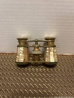 Front view of vintage opera glasses with mother-of-pearl barrels and brass fittings, showing compact size and condition.