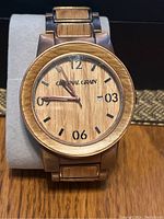 Front view of Original Grain wristwatch showing wooden dial with Arabic numerals and date display.