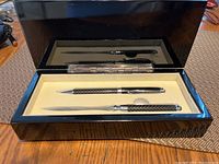 Pen and letter opener inside an open black glossy box with a beige interior.