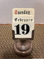 Front view of the perpetual card calendar showing the day Tuesday, month February, and date 19.