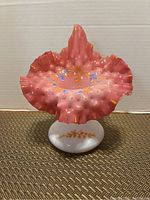 Front view of the pink ruffled Jack in Pulpit vase with gold hand painted accents on a woven mat background.