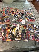 Full view of all comic books laid out on a glass surface showing different covers and titles.