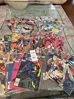Wide view of all 30 Marvel comics laid on a glass table, showing various characters and colorful covers.