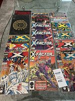 Top-down view of 17 Marvel comic books, predominantly X-Factor series with distinctive colorful covers including characters in action poses and story titles.
