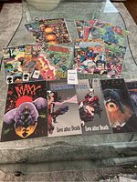 Photo showing a collection of 16 comic books including Marvel and others arranged on a glass table.