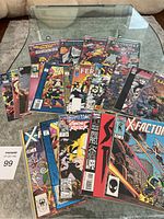 Photo showing 20 comic books fanned out on table with various titles visible including X-Factor, Ghost Rider.