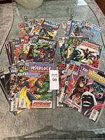 Bundle of 30 Marvel comic books displayed on a glass table, includes Warlock, X-Factor, Man-Beast themes.
