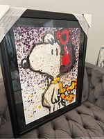 Frontal view of framed lithograph showing Snoopy artwork with corner protectors in place