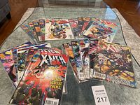 Top-down photo showing 20 X-Men comic books spread on glass table, covers visible with various X-Men characters.