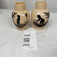 Pair of cream satin glass vases each with black hand painted silhouette scenes of children and trees.