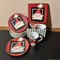 Photo of set with two plates displayed and one mug placed outside the box, showing the Santa face design and packaging box
