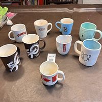 Photo showing all nine mugs arranged on a brown surface