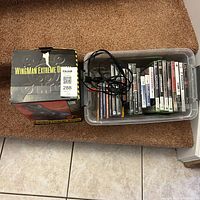 Photo of WingMan Extreme joystick box and plastic bin with video games and cables