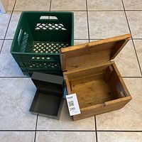 Overview of three storage items: green plastic milk crate, black metal card holder box, wooden box with hinged lid