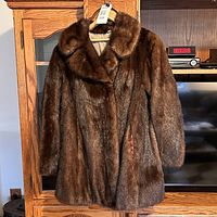 Front view of the brown mink fur coat jacket hung on a hanger showing its length and fur texture.