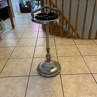 Full view of the vintage mid century modern standing ashtray on tiled floor, showing the silver-tone metal stand with decorative base and black removable ashtray at the top.
