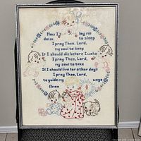Full framed needlepoint of the Lord's Prayer with decorative children and floral motifs.