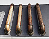 Four old oak handles lined up showing wood and brass hardware with mounting flanges and curved brass end fittings.
