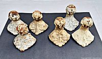 Top view of six old cast iron clawfoot bathtub feet showing worn paint and aged patina.