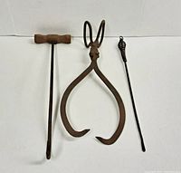 Front view of all three items: antique metal ice tongs, metal bail hook with wooden handle, and metal fire poker, showing size and wear.