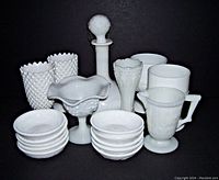 Front view of entire milk glass lot showing all 18 pieces arranged together with black background