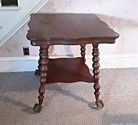 View of the oak table showing the scalloped edges of the top and the turned legs with claw feet holding glass balls.