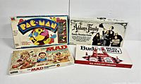 Four vintage board games laid out: PAC-MAN, MAD Magazine, Addams Family, Bud Light Checkers