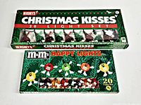 Top view showing both Hershey's Christmas Kisses and M&M's Happy Lights boxed 20-bulb string light sets on white background.