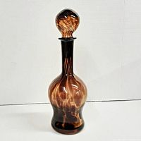 Photo of vintage brown amber glass decanter bottle with stopper on, showing swirl pattern and shape.